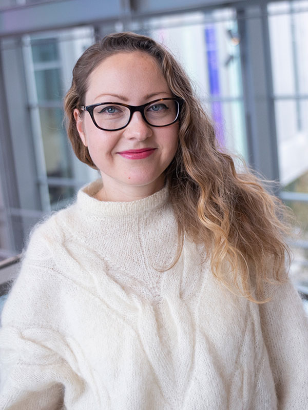 A headshot of Natasha Rubanova, who wears a white sweater and black glasses.